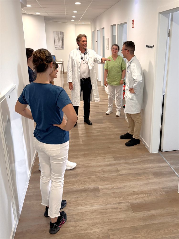 Arzt und Kolleginnen im Gespräch auf dem Praxisflur